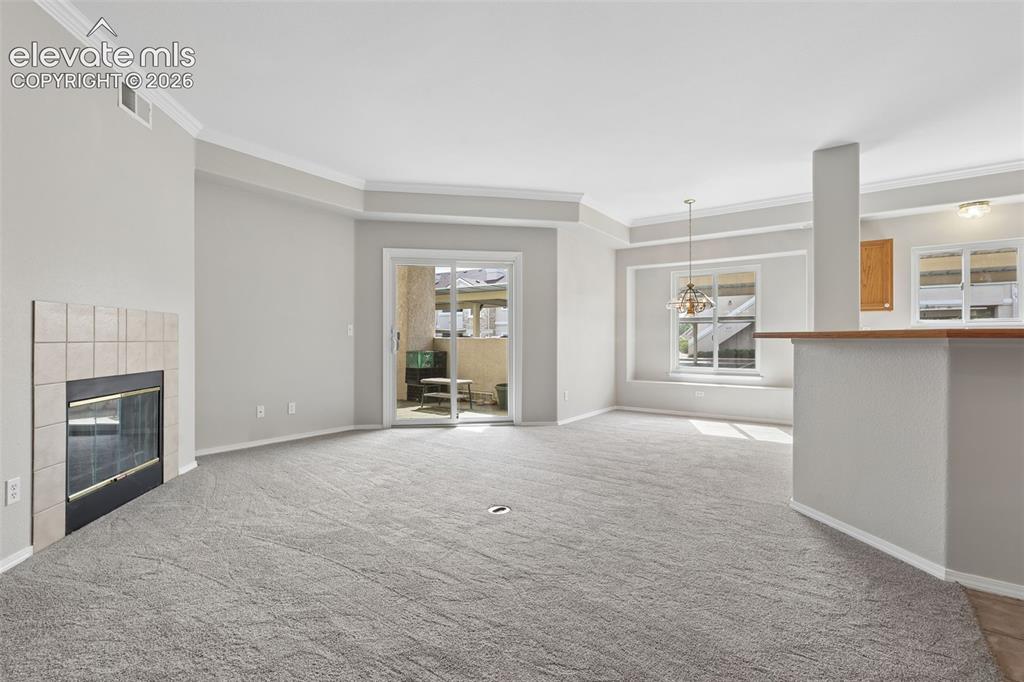 Image 3 of 27: Living room with a tiled fireplace, crown molding, and light gray carpeting