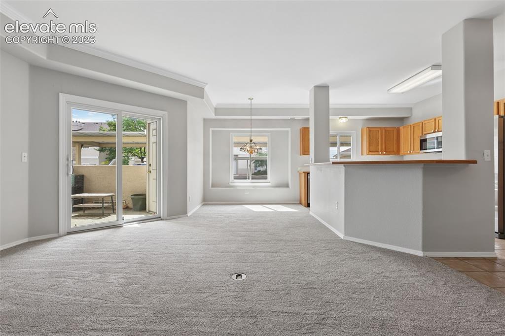 Image 4 of 27: Sliding glass door to outdoor space, crown molding, kitchen with wood cabin