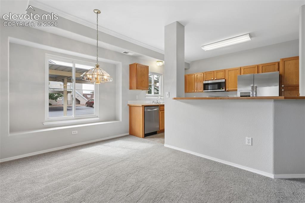 Image 6 of 27: Recessed window with deep sill, overhead chandelier, light wood-finish cabi