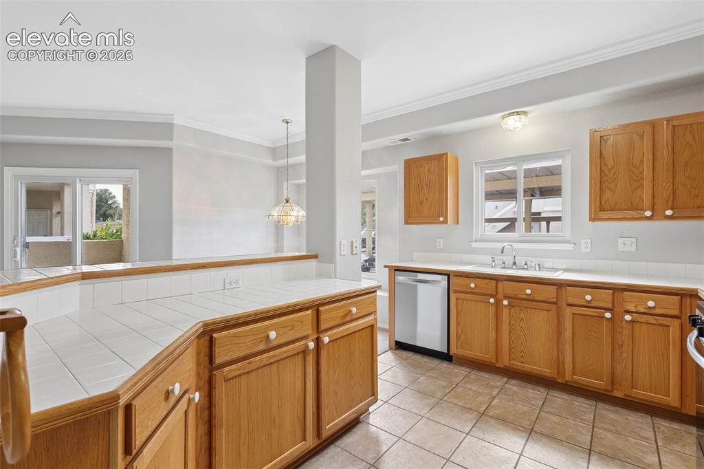 Image 7 of 27: Kitchen with wood-finish cabinetry, tile countertops, and a stainless steel