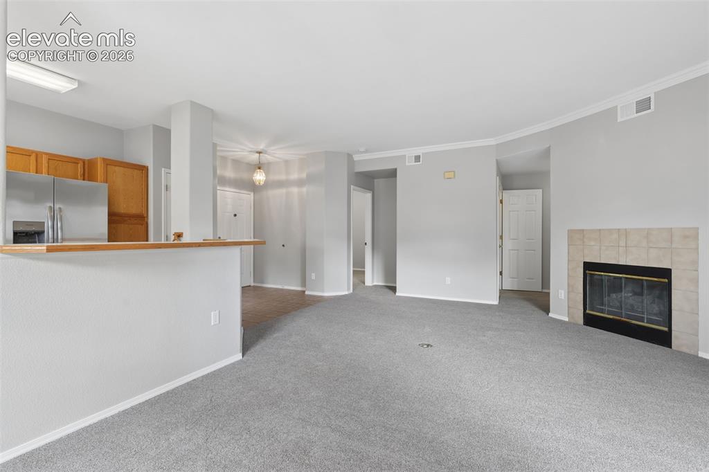 Image 9 of 27: Warm wood cabinetry, stainless steel refrigerator, and a tiled fireplace