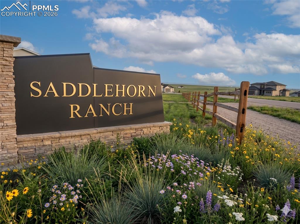 Caption: Welcoming entrance sign to the community with stone detailing, a variety of colorful plantings, and 