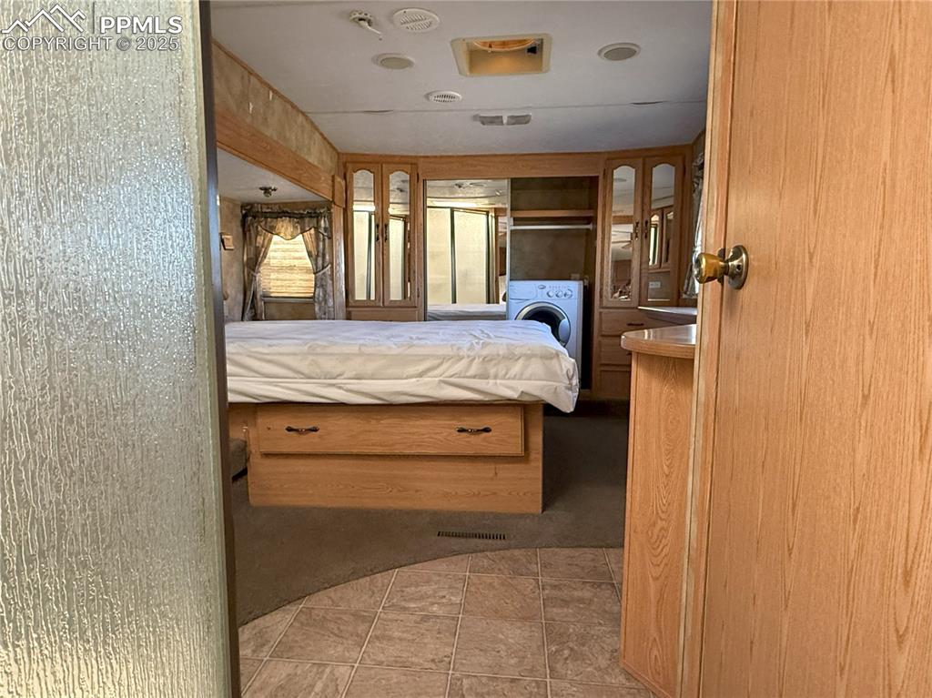 Image 13 of 15: Bedroom featuring washer / dryer, ensuite bathroom, and light tile patterne