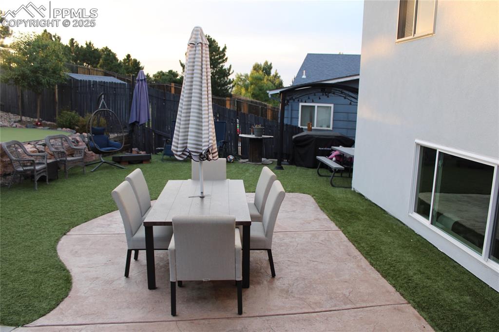 Image 18 of 26: Fenced backyard featuring outdoor dining space and a patio area