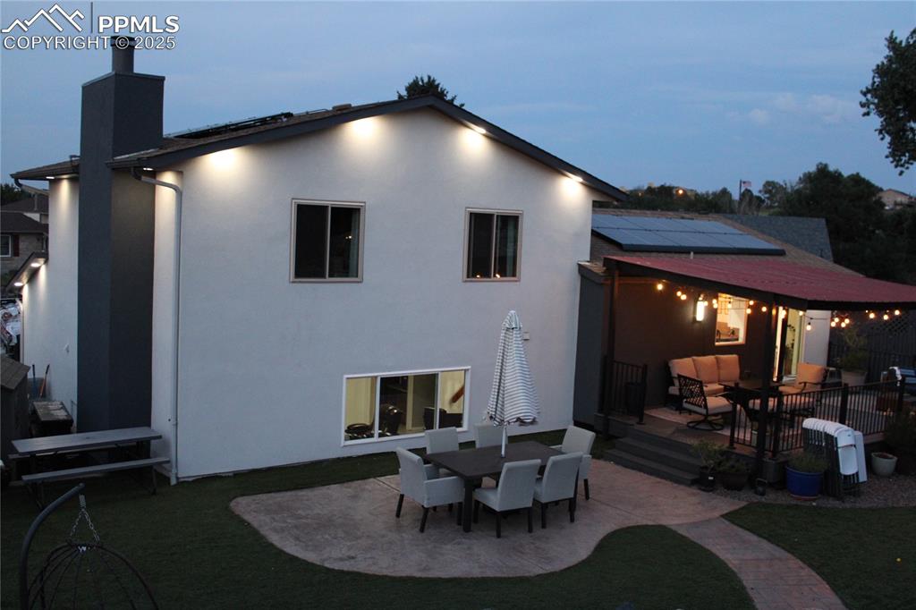 Image 22 of 26: Rear view of house with solar panels, a patio, stucco siding, an outdoor li