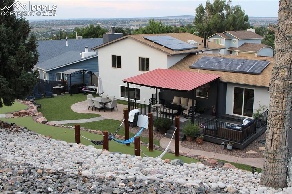 Image 25 of 26: Back of property with solar panels, stucco siding, a patio, outdoor dining