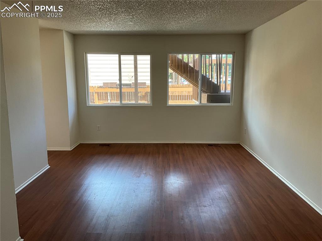 Image 8 of 13: Empty room featuring dark wood finished floors and a textured ceiling