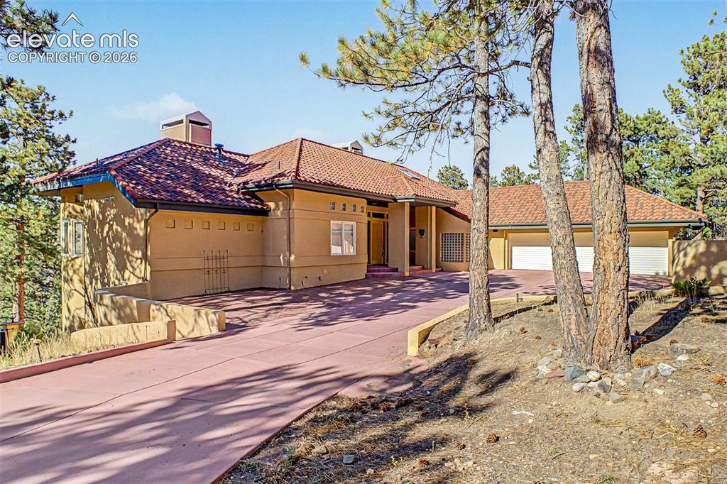 Caption: Stucco exterior with a terracotta tile roof, an attached three-car garage, an extended driveway, and