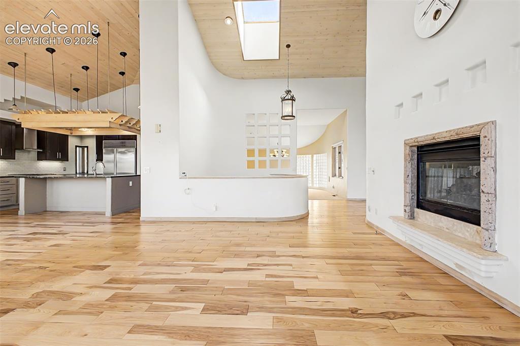 Image 10 of 50: Hardwood flooring throughout, a stone-framed fireplace, a skylight, a kitch