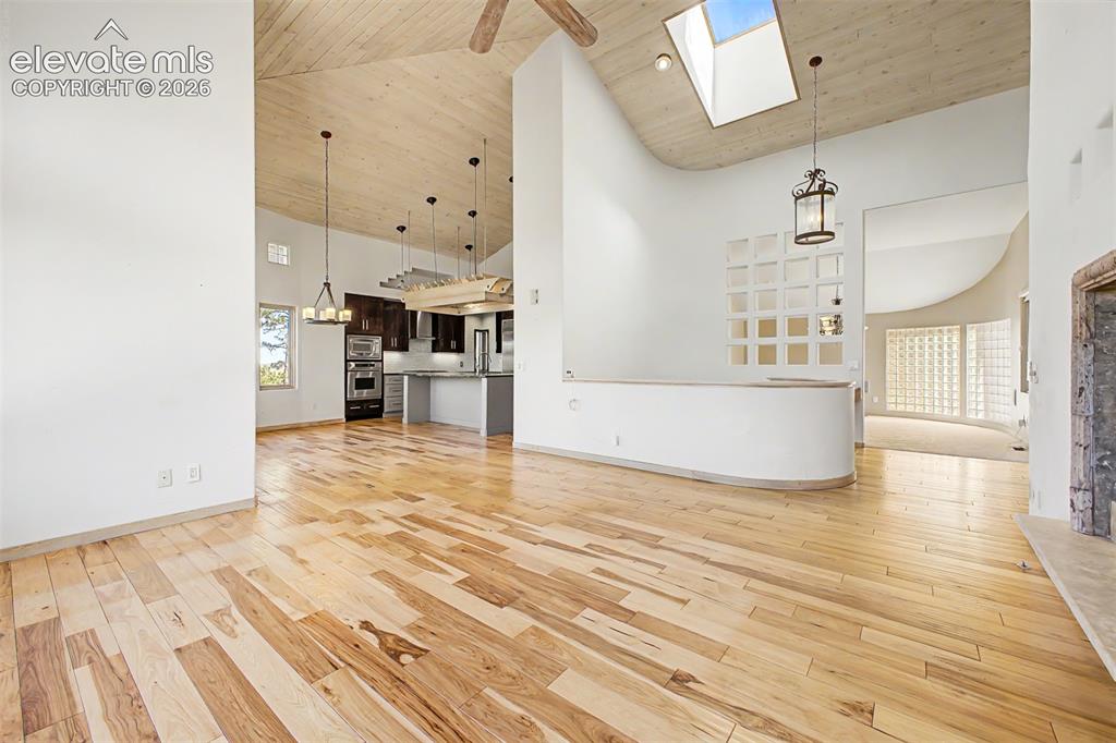 Image 11 of 50: Vaulted wood-paneled ceilings, natural wood-finish flooring, and a skylight