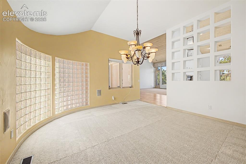 Image 13 of 50: Vaulted ceiling with an ornate chandelier, curved wall with glass block win
