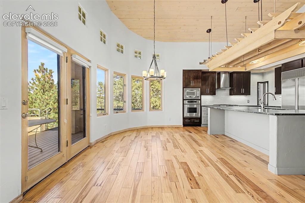Image 15 of 50: Hardwood flooring, curved wall with multiple windows, glass-paneled patio d