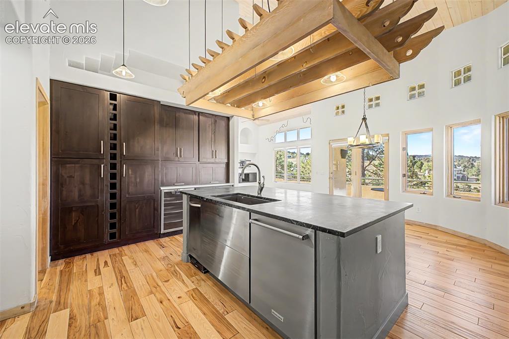 Image 18 of 50: High ceilings with exposed wooden beams, dark wood cabinetry with integrate