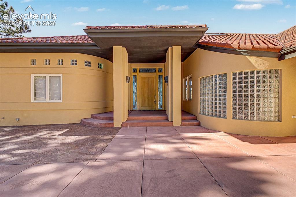 Image 2 of 50: Stucco exterior with a tile roof, an inviting covered entryway, and a promi