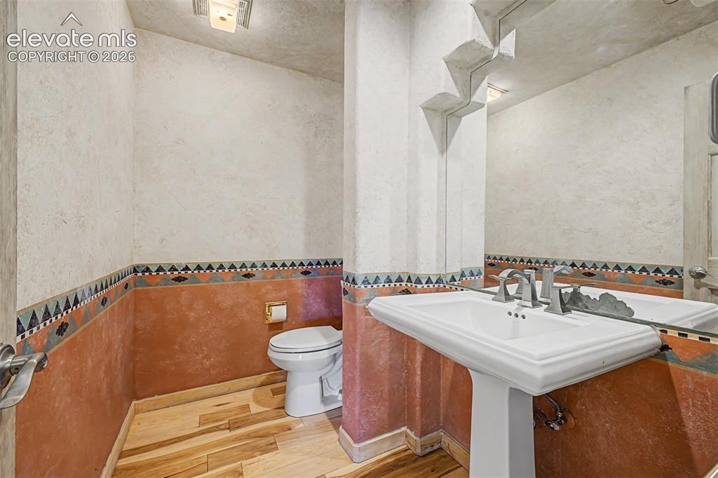 Image 21 of 50: Pedestal sink with brushed nickel fixtures, wood-finish flooring, and decor