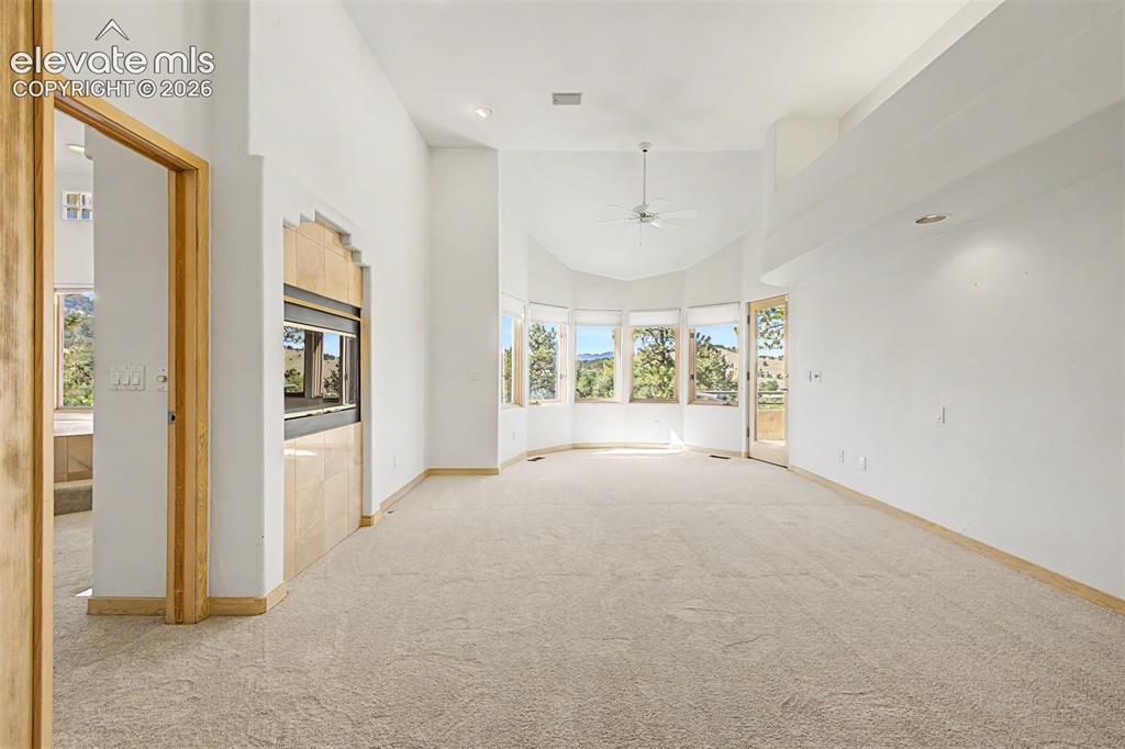 Image 23 of 50: Spacious room with vaulted ceilings, a built-in fireplace featuring stone-l