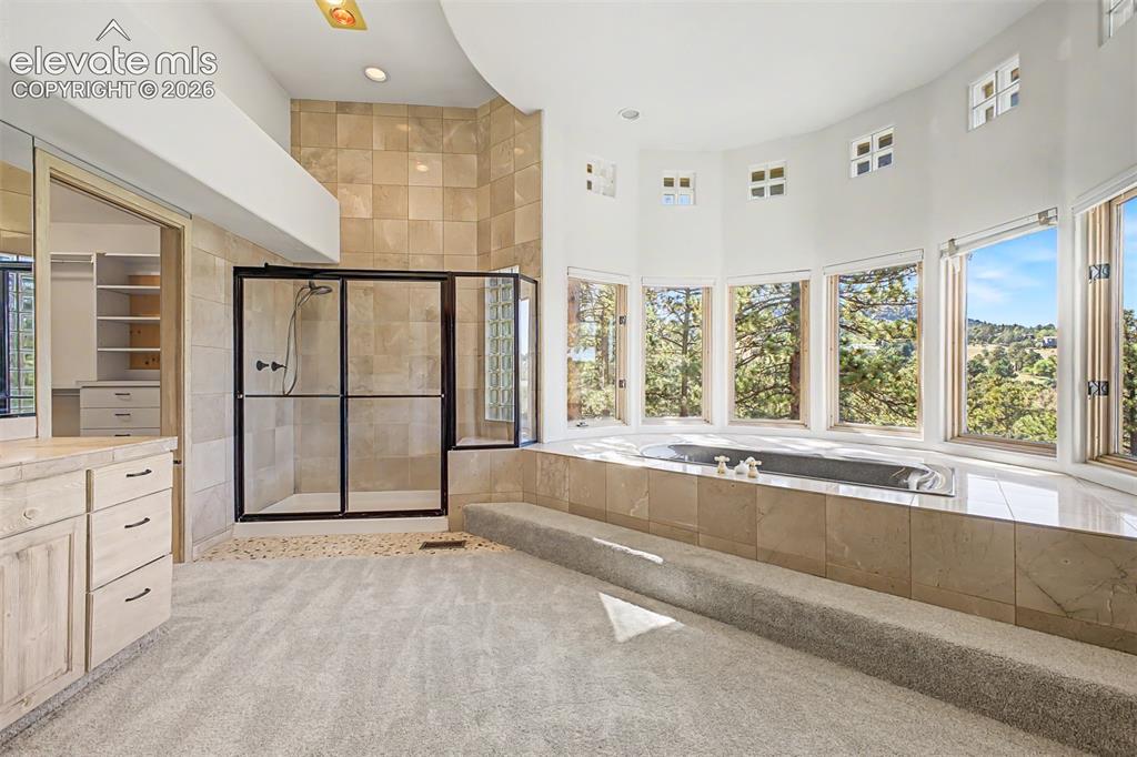 Image 26 of 50: Curved wall with multiple large windows, a built-in soaking tub, a separate