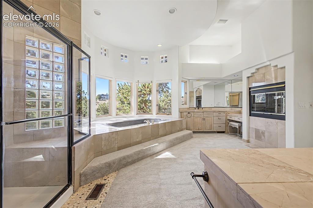 Image 28 of 50: Built-in soaking tub, glass-enclosed shower, dual vanity with undermount si
