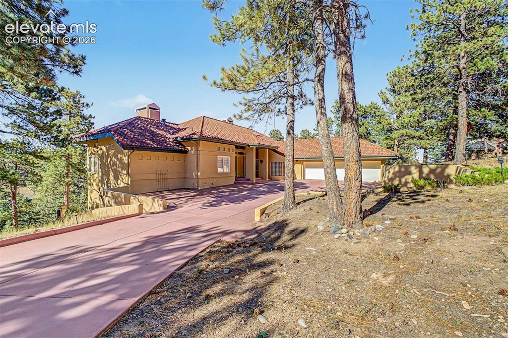 Image 3 of 50: Mediterranean-style exterior featuring a terracotta tile roof, stucco finis