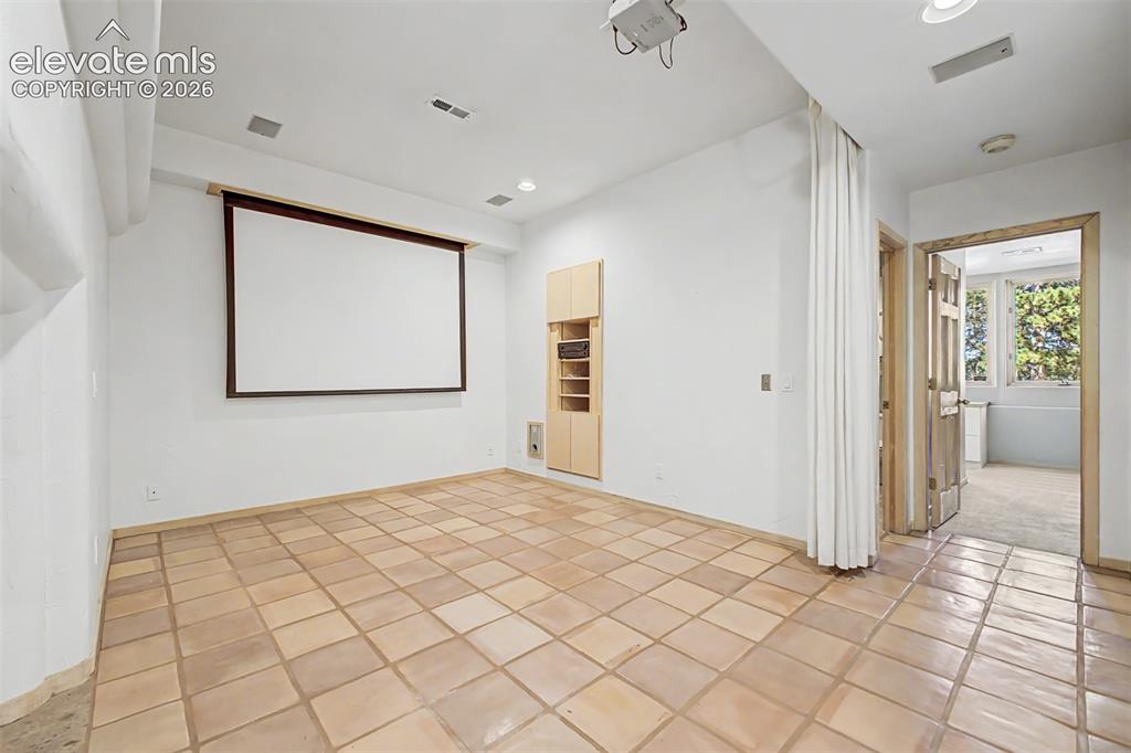 Image 37 of 50: Media room with a projection screen, ceiling-mounted projector, and built-i