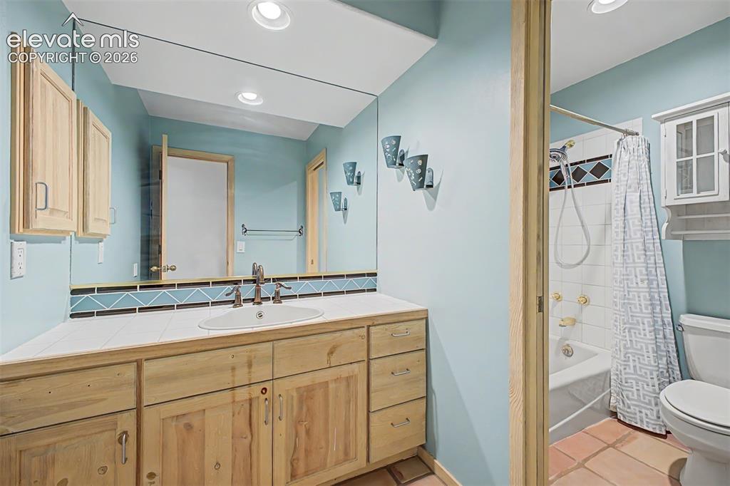 Image 39 of 50: Wood-finish vanity with an integrated sink, large wall mirror, and recessed