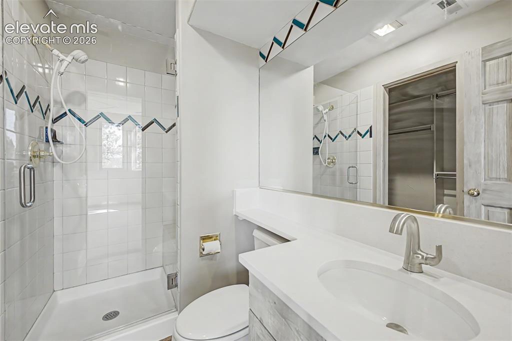 Image 40 of 50: Glass-enclosed shower with tile surround, vanity with integrated sink, and