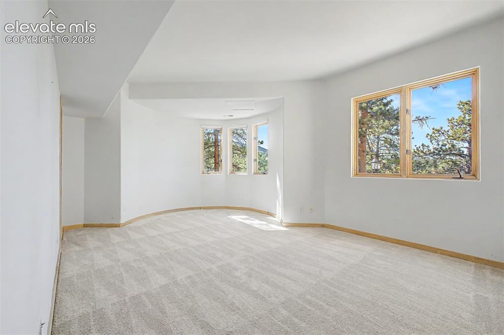 Image 42 of 50: Spacious room with light-toned patterned carpeting and multiple large windo