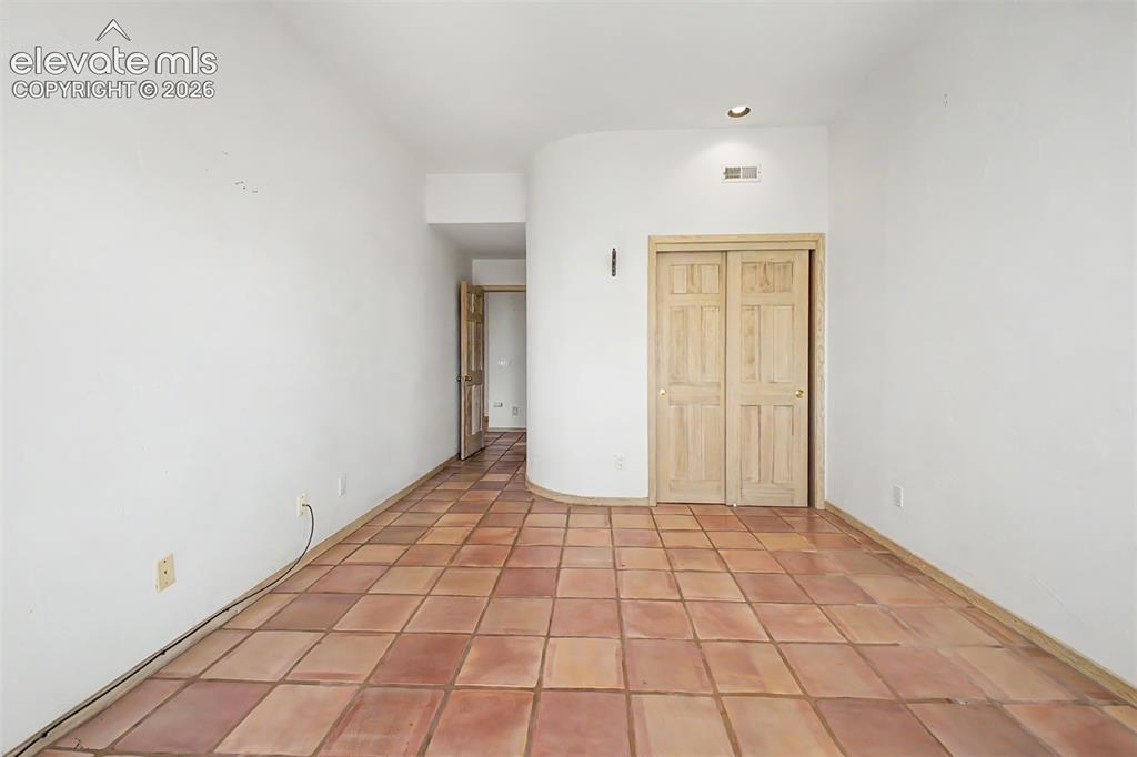 Image 45 of 50: Terra cotta tile flooring, recessed lighting, and light wood-paneled bi-fol