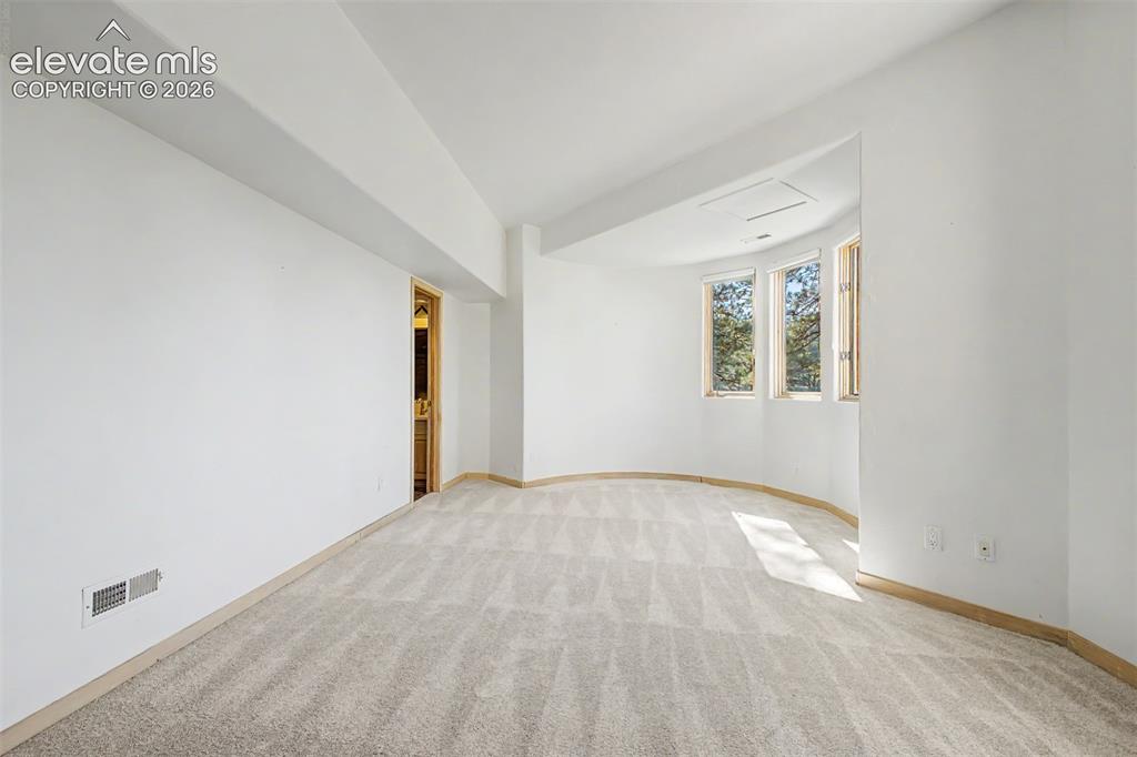 Image 46 of 50: Curved architectural wall with three windows, neutral carpet flooring, and 