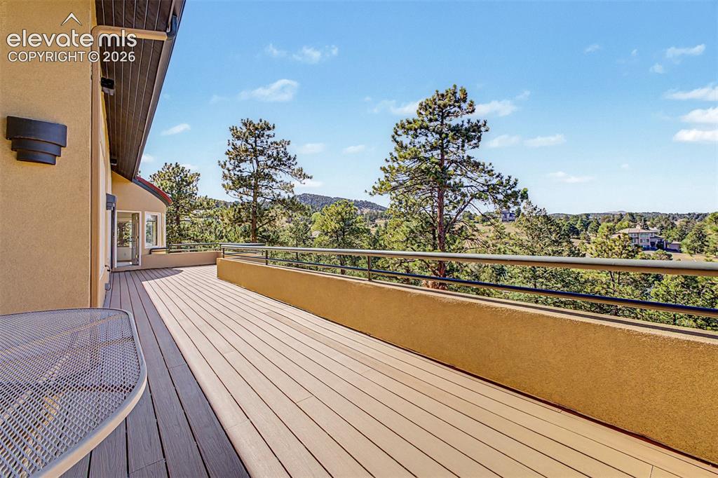 Image 47 of 50: Expansive exterior deck with composite decking, a stucco half-wall, and a m