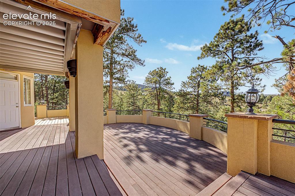 Image 49 of 50: Expansive outdoor decking featuring a curved railing, stucco exterior, and 