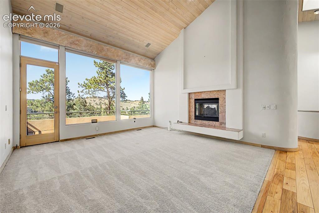 Image 6 of 50: Vaulted wood-finish ceiling, expansive windows, built-in fireplace with sto