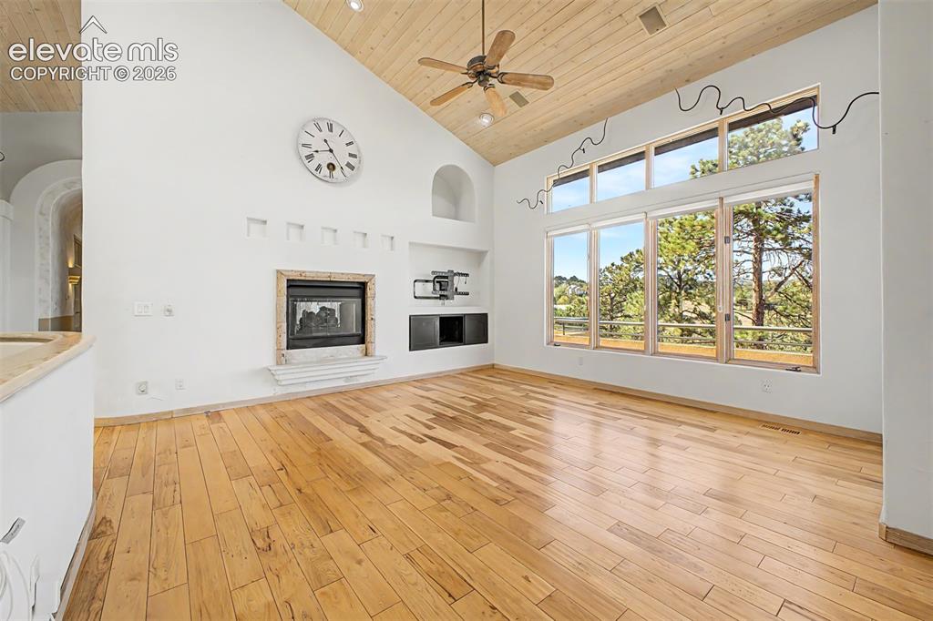 Image 8 of 50: Vaulted wood-paneled ceiling, wood-finish flooring, built-in fireplace, exp