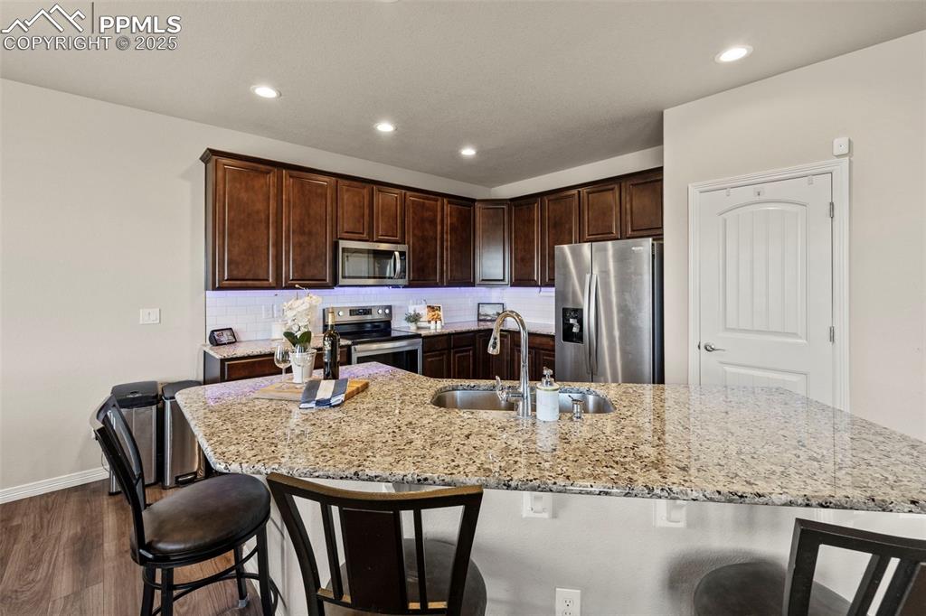 Image 10 of 36: Kitchen featuring a breakfast bar, stainless steel appliances, and dark cab