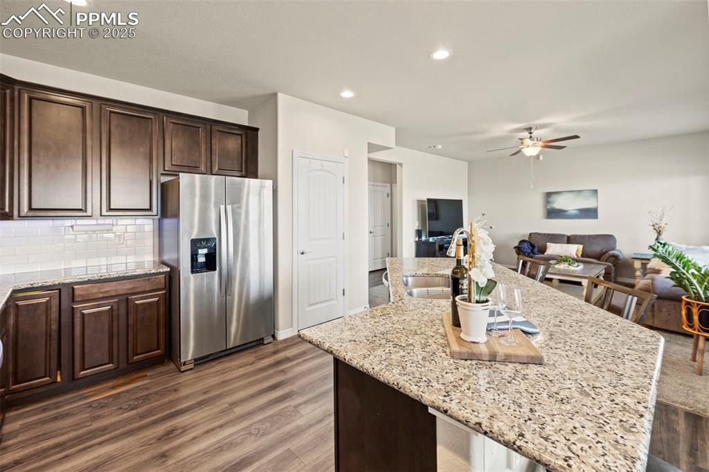 Image 12 of 36: Kitchen with a ceiling fan, a sink, light stone counters, stainless steel f