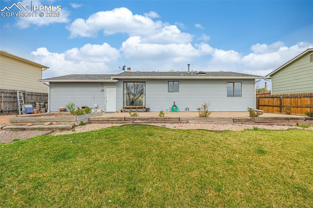 Image 18 of 21: Back of house features fenced yard, concrete patio, flat grassy space and p
