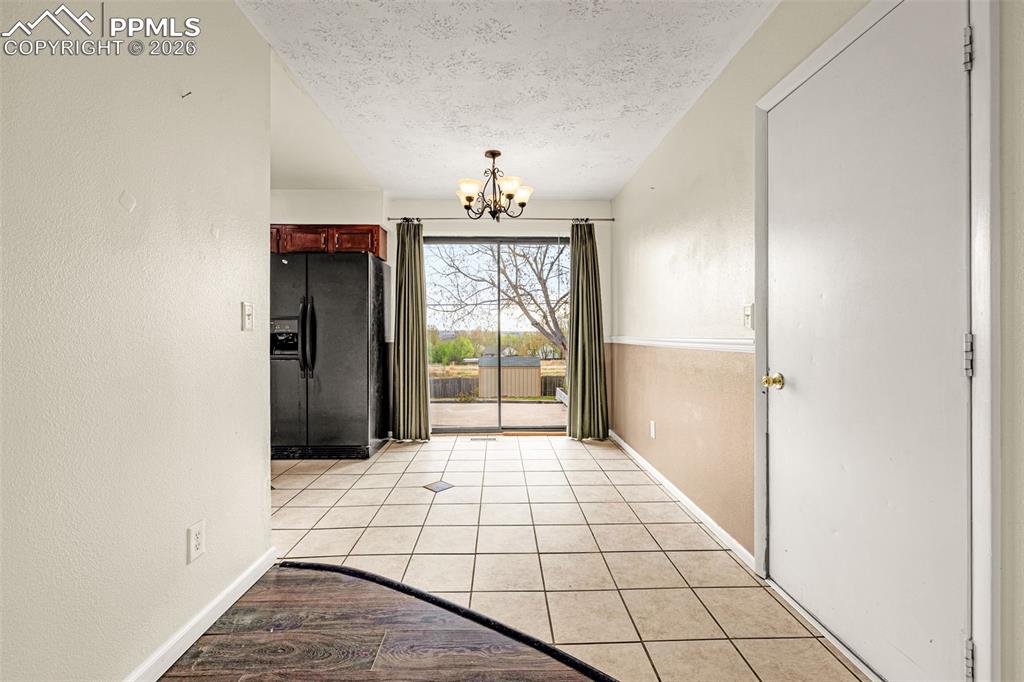 Image 9 of 21: Dining area with walkout to back patio, tile floor and door to garage
