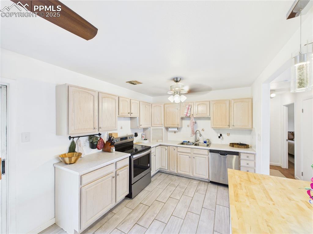 Image 10 of 41: Kitchen featuring stainless steel appliances, light brown cabinetry, light 