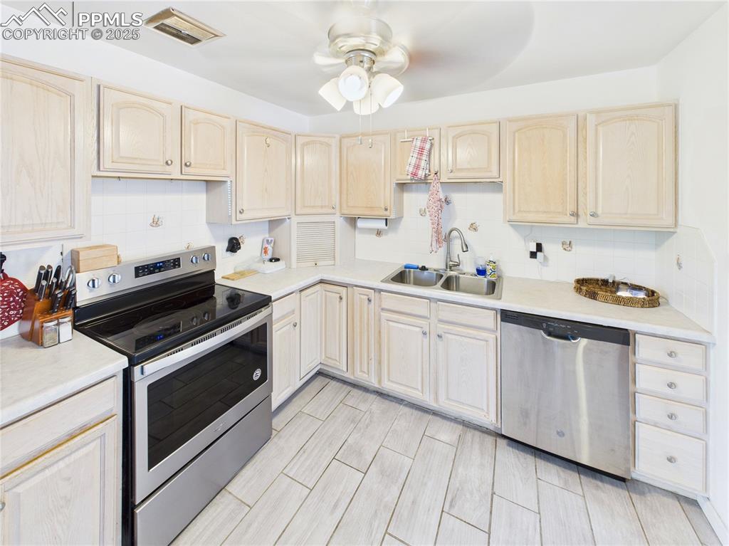 Image 13 of 41: Kitchen with stainless steel appliances, light brown cabinets, a ceiling fa