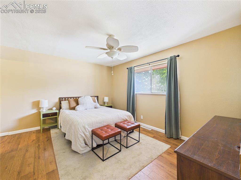 Image 19 of 41: Bedroom with light wood finished floors and a ceiling fan