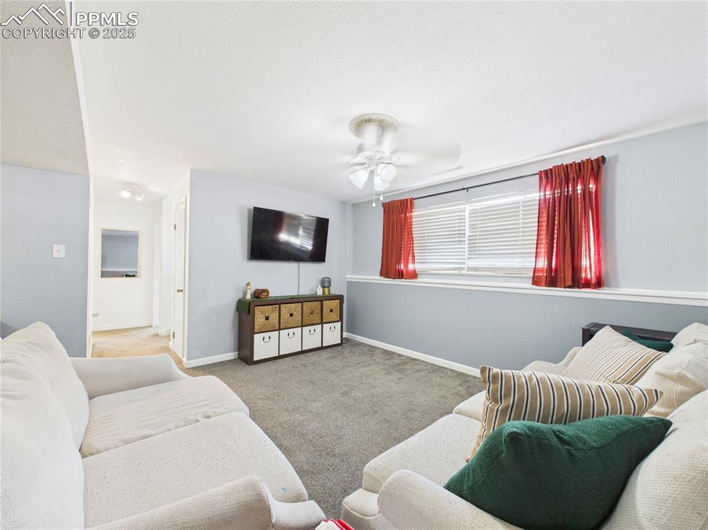 Image 35 of 41: Carpeted living area featuring baseboards and ceiling fan