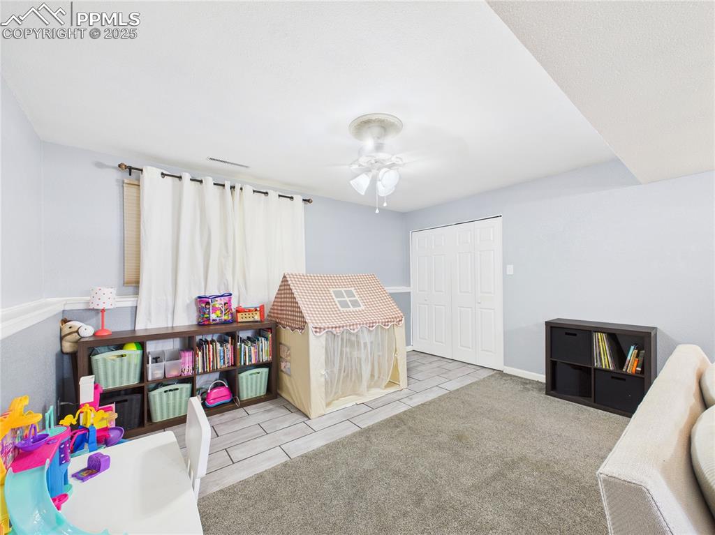 Image 36 of 41: Recreation room with a ceiling fan, carpet flooring, and tile patterned flo