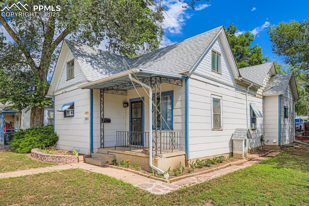 Caption: View of front of house featuring roof with shingles, a front yard, and a porch