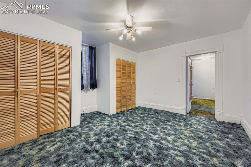 Image 14 of 28: Unfurnished bedroom featuring multiple closets, dark colored carpet, and a