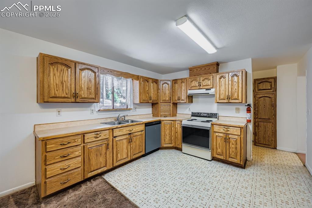 Image 9 of 28: Kitchen featuring light countertops, brown cabinetry, electric range, dishw