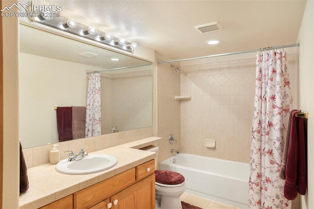 Image 26 of 33: Large full bath in basement features tiled vanity countertop, tiled tub/sho