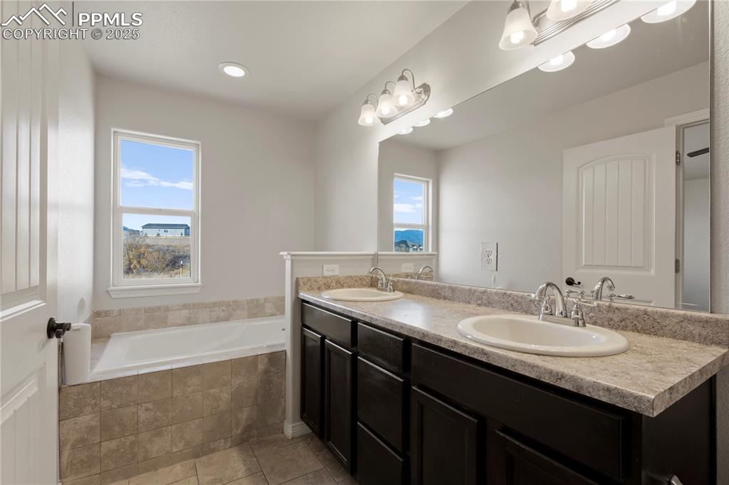 Image 20 of 35: Bathroom with double vanity, a bath, light tile patterned floors, and reces