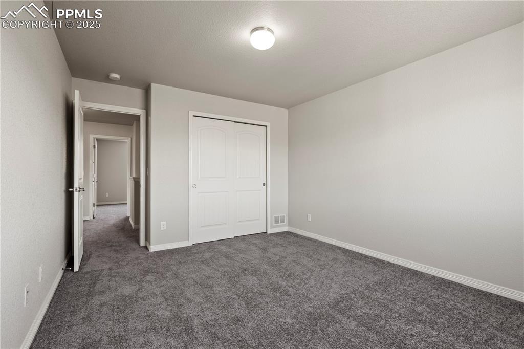 Image 25 of 35: Unfurnished bedroom with dark carpet and a closet