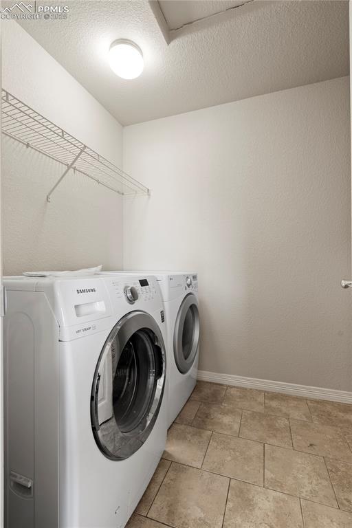 Image 26 of 35: Laundry area with a textured ceiling, independent washer and dryer, and lig