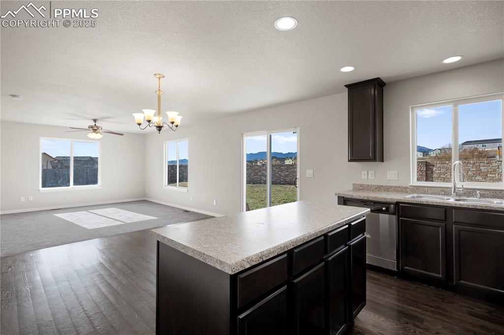 Image 8 of 35: Kitchen featuring a textured ceiling, a kitchen island, dishwasher, decorat